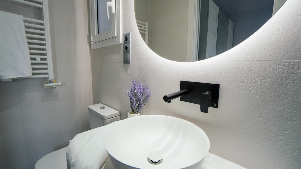 This is an example of a mid-sized contemporary master bathroom in Barcelona with flat-panel cabinets, white cabinets, a curbless shower, a one-piece toilet, blue tile, ceramic tile, white walls, concrete floors, a vessel sink, laminate benchtops, grey floor, a sliding shower screen, white benchtops, an enclosed toilet, a single vanity and a freestanding vanity.