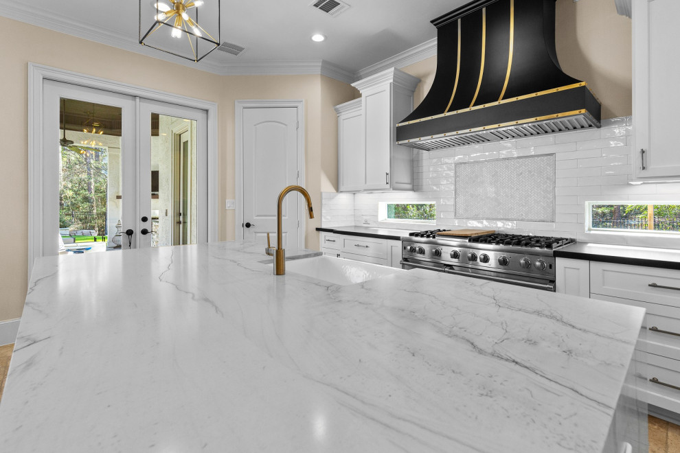 Large transitional l-shaped limestone floor and beige floor eat-in kitchen photo in Houston with a farmhouse sink, recessed-panel cabinets, white cabinets, quartzite countertops, white backsplash, limestone backsplash, stainless steel appliances, an island and white countertops
