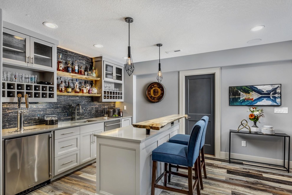 Photo of a mid-sized contemporary single-wall wet bar in Portland with an undermount sink, shaker cabinets, grey cabinets, quartzite benchtops, black splashback, subway tile splashback, vinyl floors, brown floor and grey benchtop.