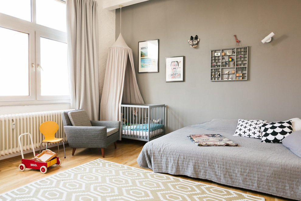 Design ideas for a mid-sized contemporary gender-neutral nursery in Berlin with grey walls, medium hardwood floors and brown floor.