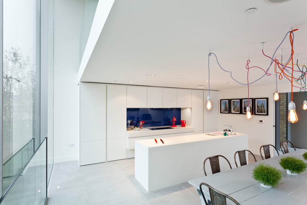 This is an example of a scandinavian galley eat-in kitchen in Orange County with an integrated sink, flat-panel cabinets, white cabinets, blue splashback, glass sheet splashback and panelled appliances.