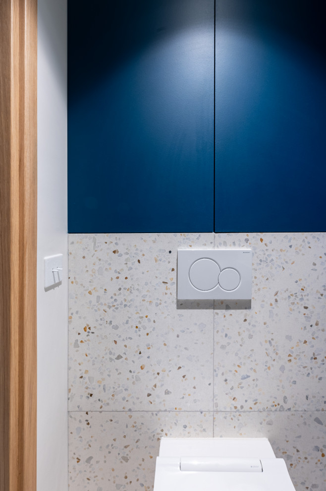 Idée de décoration pour un petit WC suspendu design avec un placard à porte affleurante, des portes de placard bleues et meuble-lavabo encastré.