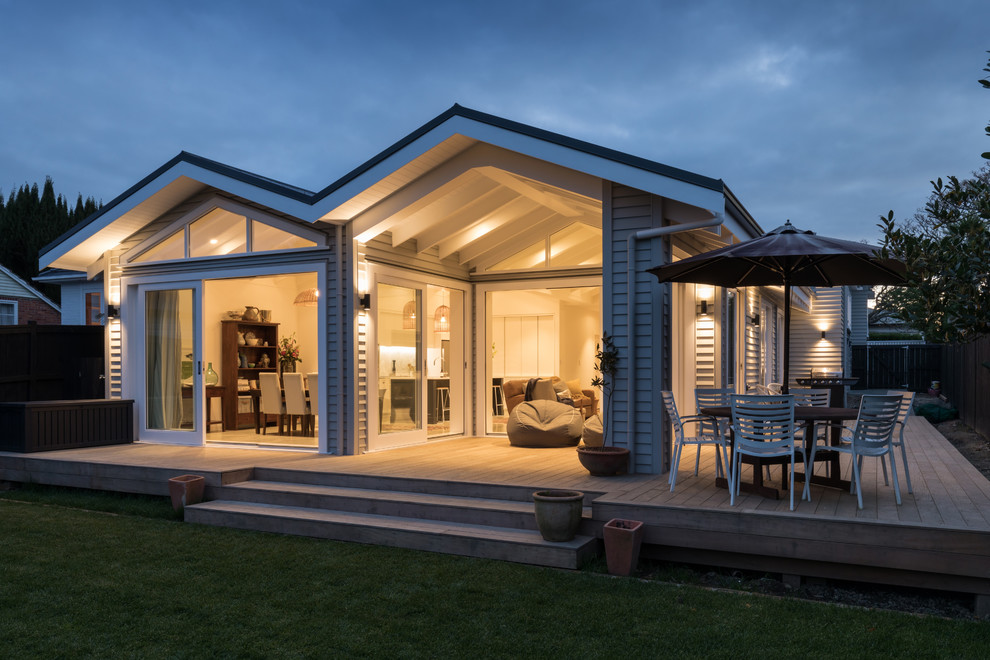 This is an example of a mid-sized contemporary backyard deck in Auckland with a roof extension.