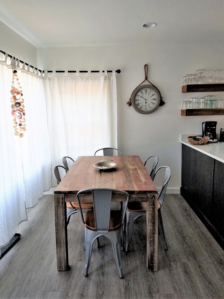 Photo of a small beach style dining room with white walls, vinyl floors and grey floor.