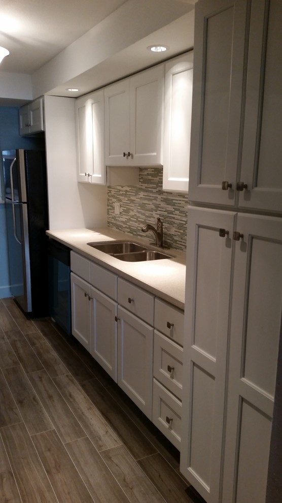 Transitional bamboo floor kitchen photo in Miami with gray backsplash, a double-bowl sink, glass tile backsplash and stainless steel appliances