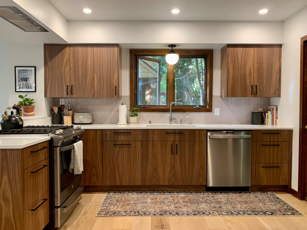 Inspiration for a small midcentury l-shaped eat-in kitchen in Other with a single-bowl sink, flat-panel cabinets, medium wood cabinets, quartz benchtops, pink splashback, ceramic splashback, stainless steel appliances, light hardwood floors, a peninsula, brown floor and white benchtop.