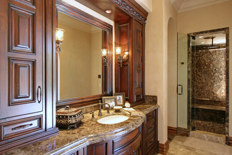 Photo of an expansive mediterranean master bathroom in Phoenix with flat-panel cabinets, light wood cabinets, a hot tub, a double shower, a one-piece toilet, beige tile, stone tile, beige walls, travertine floors, an integrated sink and tile benchtops.