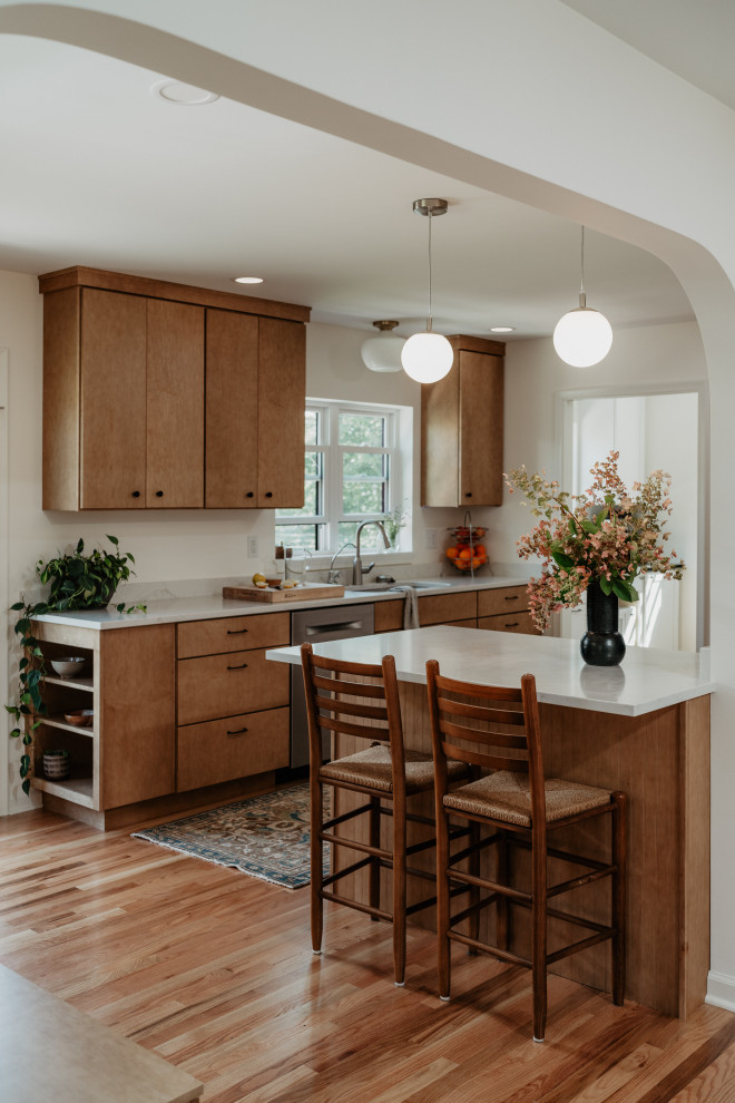 Example of a mid-sized 1950s l-shaped medium tone wood floor kitchen pantry design in Detroit with an undermount sink, flat-panel cabinets, light wood cabinets, quartz countertops, white backsplash, quartz backsplash, stainless steel appliances, a peninsula and white countertops