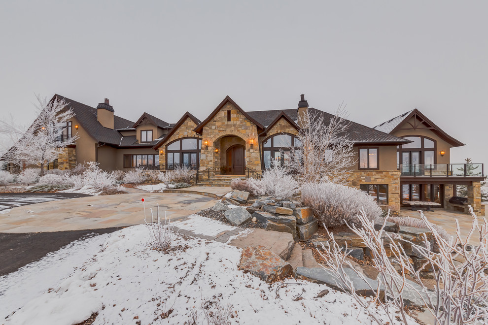 This is an example of an expansive traditional one-storey beige exterior in Calgary with stone veneer.