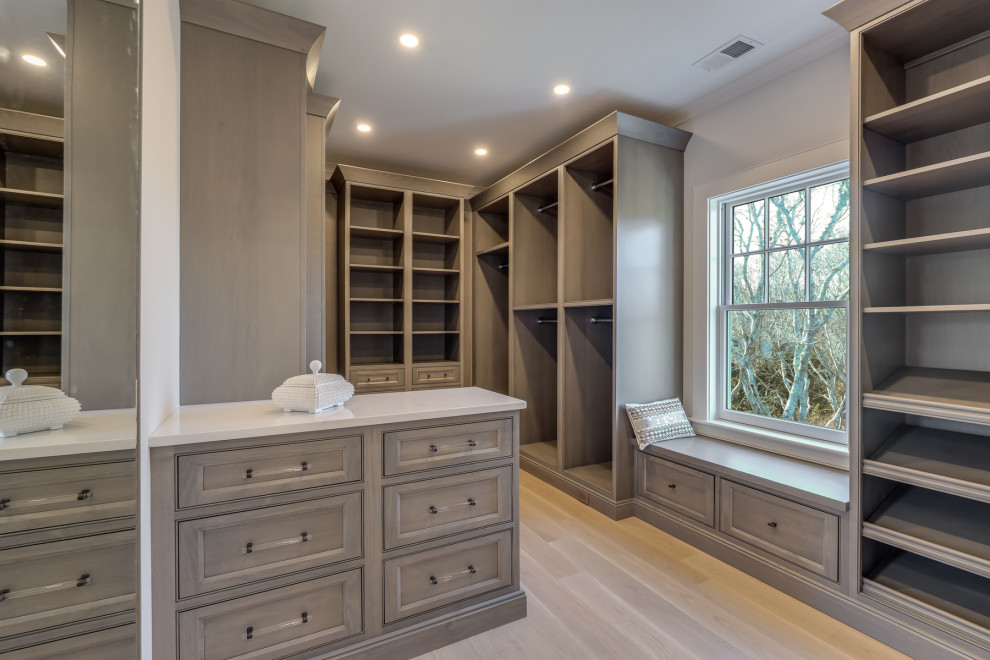 Walk-in closet - large gender-neutral light wood floor walk-in closet idea in Boston with beaded inset cabinets and medium tone wood cabinets