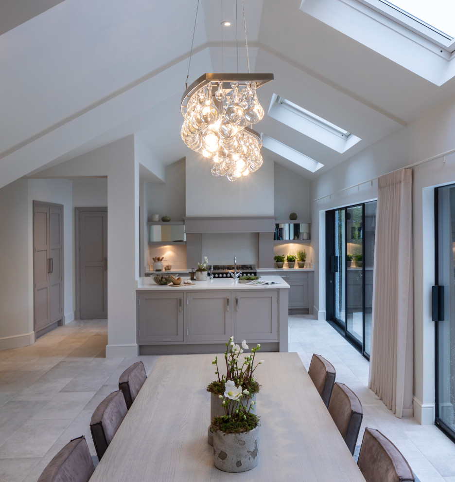 Mid-sized contemporary galley eat-in kitchen in Cheshire with a farmhouse sink, shaker cabinets, grey cabinets, marble benchtops, grey splashback, limestone splashback, black appliances, porcelain floors, with island, white floor and white benchtop.