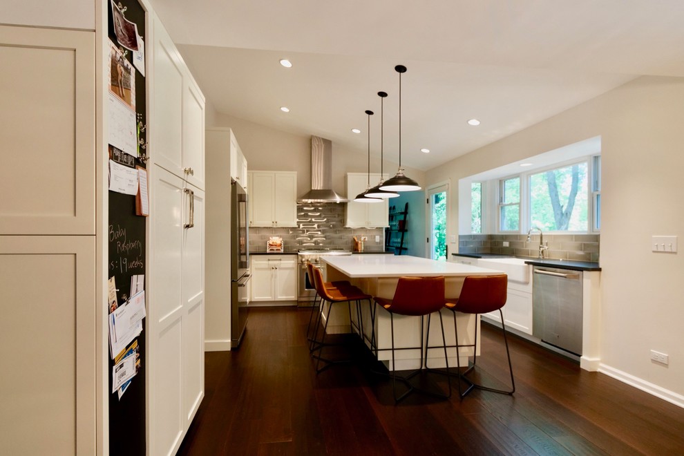 Inspiration for a small transitional kitchen in Chicago with a farmhouse sink, shaker cabinets, white cabinets, quartz benchtops, stainless steel appliances, dark hardwood floors, with island and brown floor.