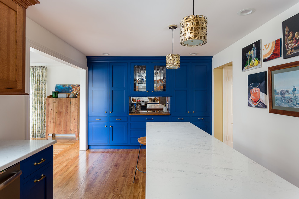 Small traditional l-shaped eat-in kitchen in Louisville with an undermount sink, shaker cabinets, blue cabinets, quartz benchtops, grey splashback, subway tile splashback, stainless steel appliances, light hardwood floors, multiple islands, brown floor and white benchtop.