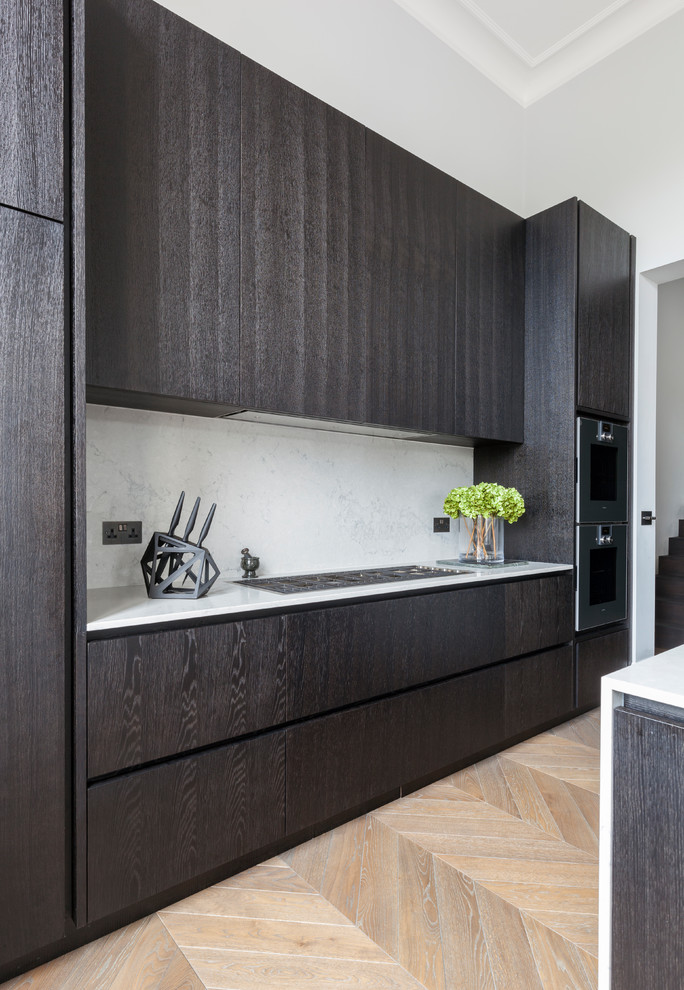 Contemporary single-wall kitchen in London with flat-panel cabinets, grey splashback, light hardwood floors, beige floor, an integrated sink, solid surface benchtops, stone slab splashback and a peninsula.