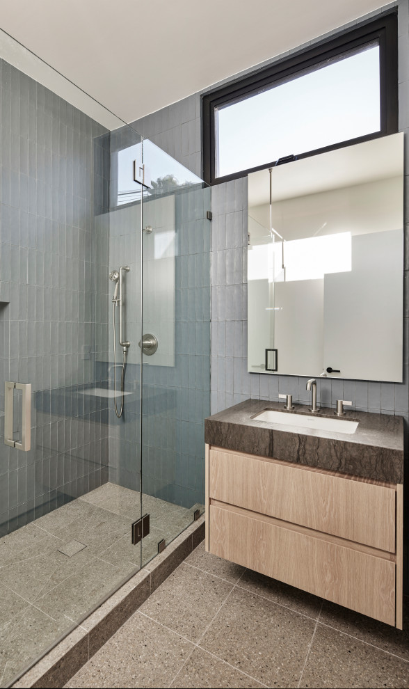 Идея дизайна: ванная комната среднего размера в стиле модернизм с плоскими фасадами, светлыми деревянными фасадами, угловым душем, унитазом-моноблоком, синей плиткой, керамической плиткой, синими стенами, полом из терраццо, врезной раковиной, столешницей из кварцита, серым полом, душем с распашными дверями, коричневой столешницей, тумбой под одну раковину, подвесной тумбой и душевой кабиной
