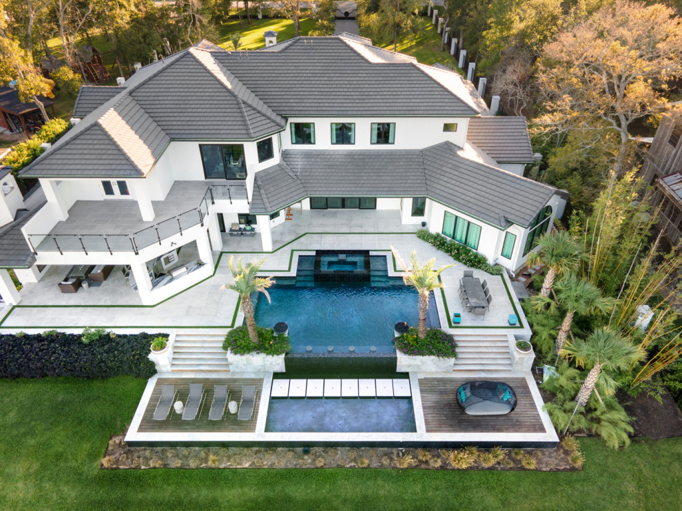 Idée de décoration pour une grande piscine arrière minimaliste sur mesure avec des pavés en pierre naturelle.