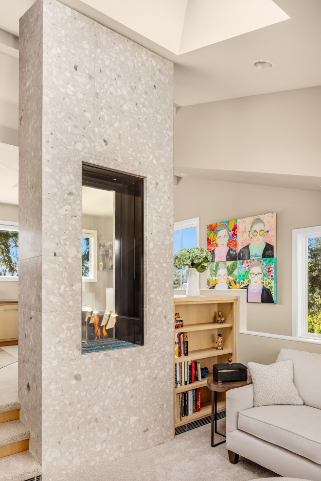 Imagen de despacho abovedado de tamaño medio con paredes beige, moqueta, chimenea de doble cara, marco de chimenea de baldosas y/o azulejos y suelo beige