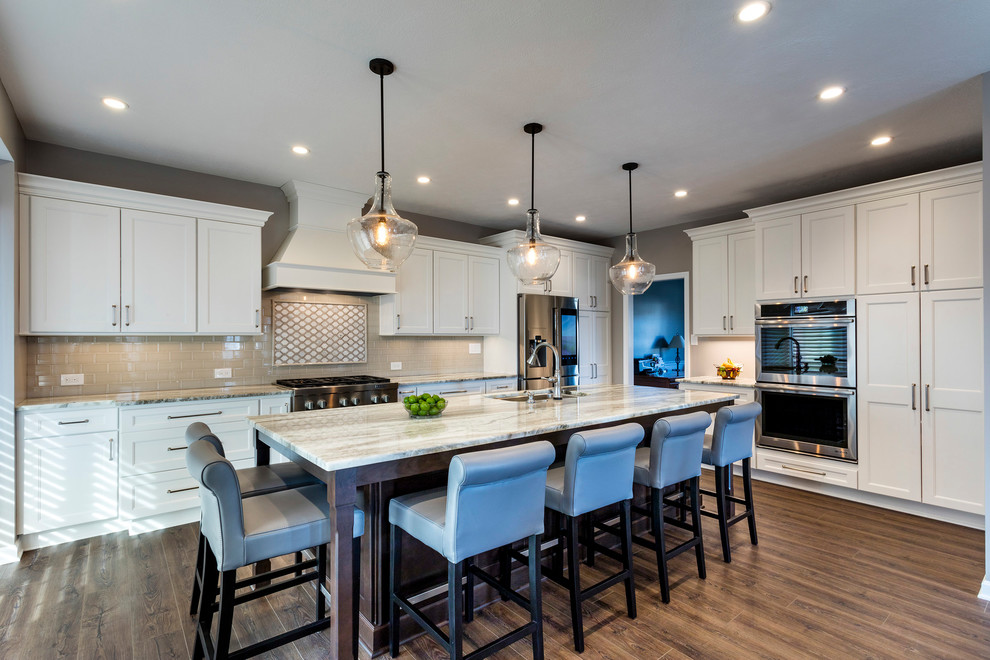 Inspiration for a large transitional vinyl floor and brown floor kitchen remodel with an undermount sink, recessed-panel cabinets, white cabinets, granite countertops, beige backsplash, ceramic backsplash, stainless steel appliances and an island