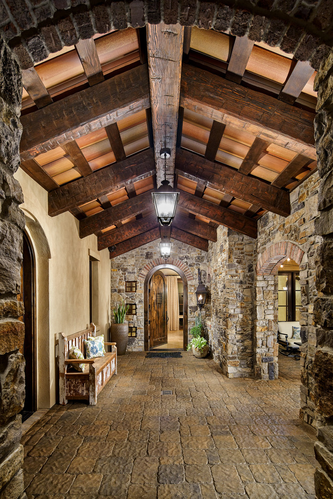 This is an example of a mediterranean foyer in Denver with brown walls and a dark wood front door.