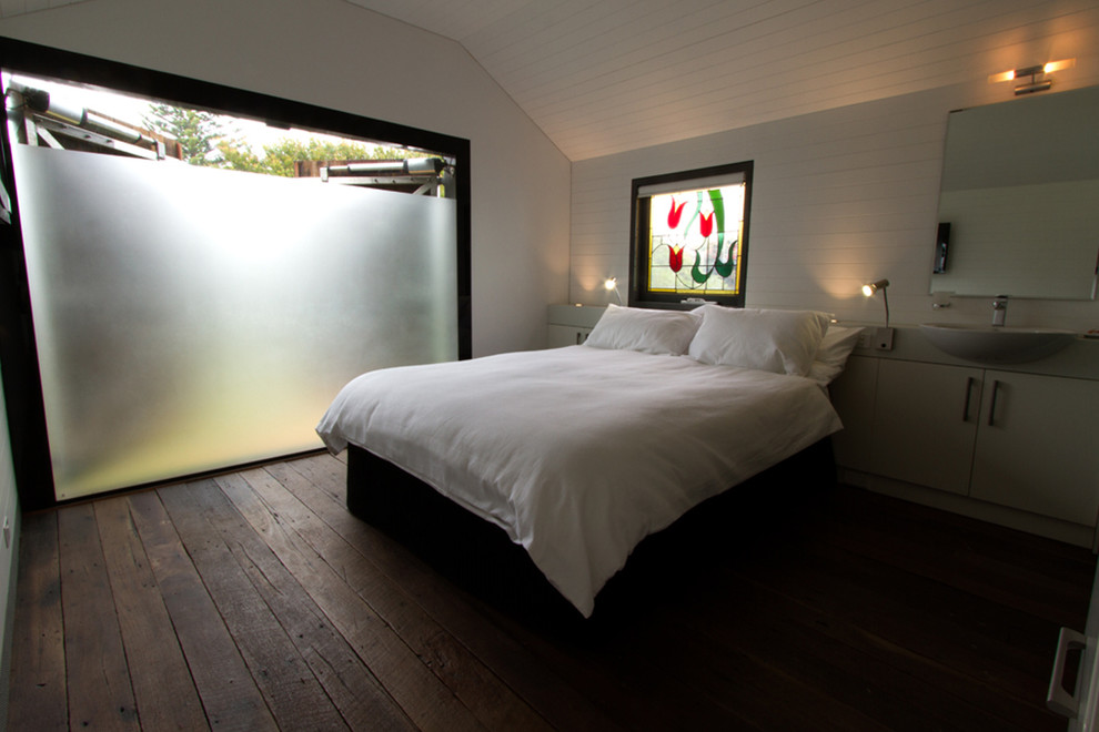 Photo of a mid-sized beach style guest bedroom in Perth with white walls and dark hardwood floors.