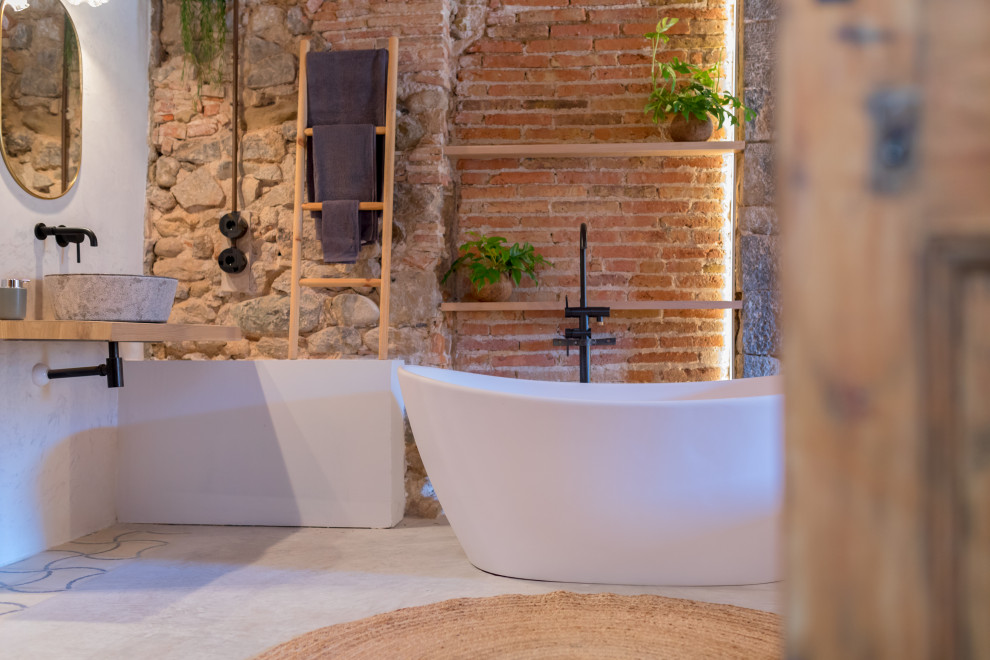 На фото: ванная комната в стиле неоклассика (современная классика) с серыми фасадами, отдельно стоящей ванной, открытым душем, инсталляцией, серой плиткой, серыми стенами, бетонным полом, настольной раковиной, столешницей из дерева, серым полом, открытым душем, сиденьем для душа, тумбой под две раковины, встроенной тумбой, балками на потолке и кирпичными стенами