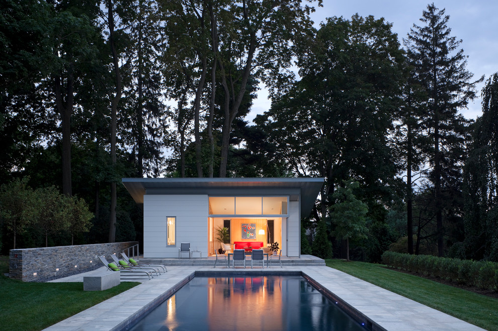 Inspiration for a mid-sized modern side yard rectangular pool in New York with natural stone pavers and a pool house.