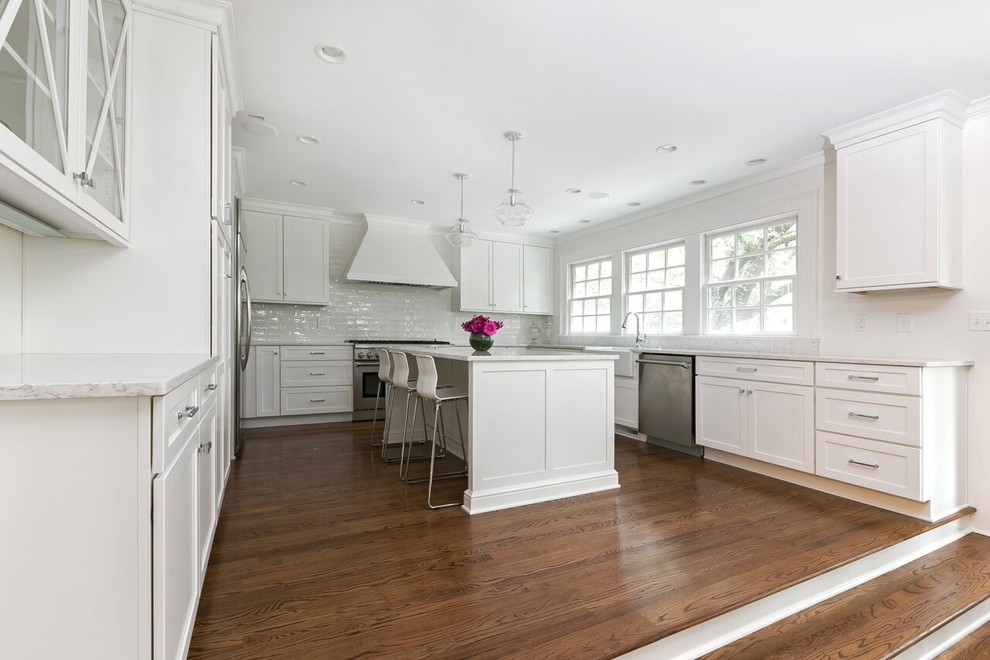 Design ideas for a large transitional u-shaped eat-in kitchen in Charleston with shaker cabinets, white cabinets, white splashback, stainless steel appliances, medium hardwood floors and with island.