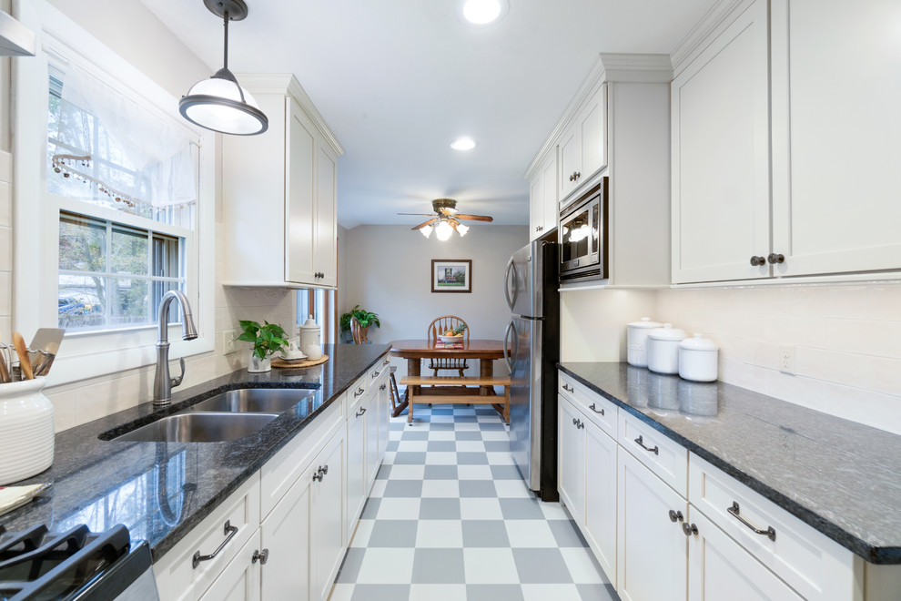 Example of a mid-sized minimalist galley ceramic tile and gray floor eat-in kitchen design in Providence with an undermount sink, recessed-panel cabinets, white cabinets, granite countertops, white backsplash, ceramic backsplash, stainless steel appliances and no island