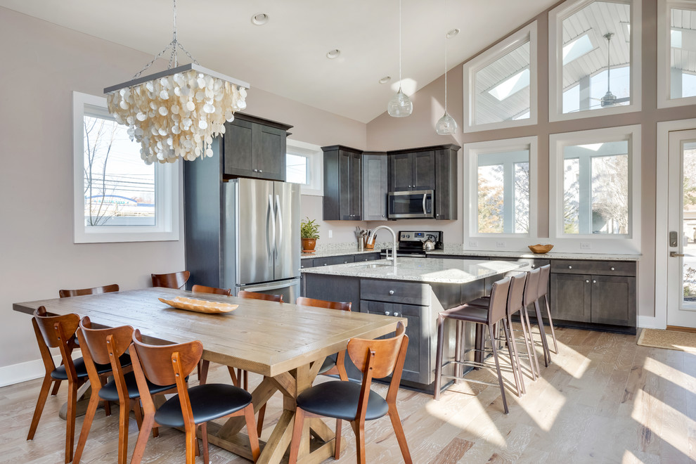 Example of a mid-sized transitional l-shaped light wood floor and brown floor open concept kitchen design with an undermount sink, shaker cabinets, gray cabinets, granite countertops, stainless steel appliances, an island and gray countertops