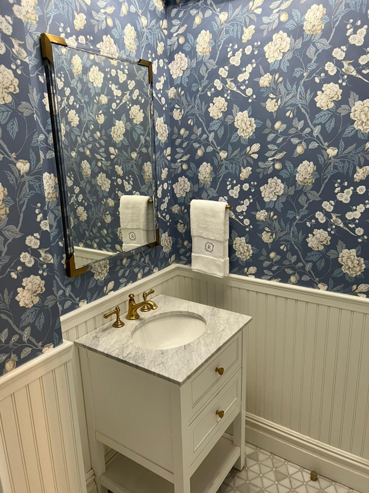 Foto på ett vintage grå toalett, med luckor med infälld panel, vita skåp, en toalettstol med hel cisternkåpa, blå väggar, marmorgolv, ett nedsänkt handfat, marmorbänkskiva och grått golv