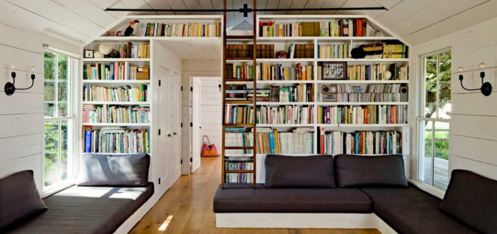 Diseño de sala de estar con biblioteca cerrada y abovedada grande sin chimenea con paredes grises, suelo vinílico, televisor colgado en la pared y suelo marrón
