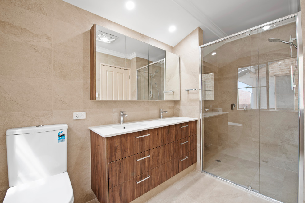 Inspiration for a mid-sized mediterranean 3/4 bathroom in Perth with dark wood cabinets, an alcove shower, a one-piece toilet, beige tile, beige walls, an undermount sink, solid surface benchtops, beige floor, a hinged shower door and white benchtops.