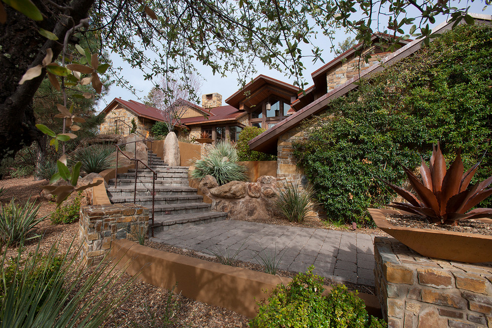 This is an example of a mid-sized country split-level brown exterior in Phoenix with stone veneer and a gable roof.