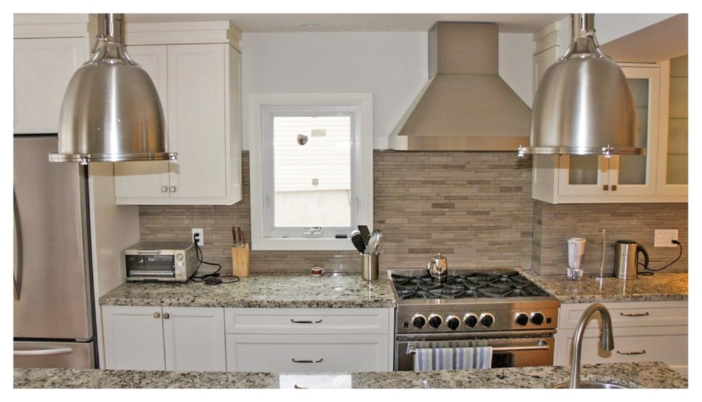 Example of a mid-sized transitional galley kitchen design in Toronto with an undermount sink, shaker cabinets, white cabinets, solid surface countertops, beige backsplash, stone tile backsplash, stainless steel appliances and a peninsula