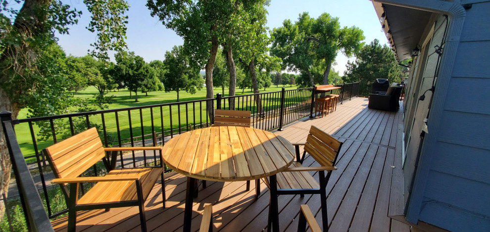 This is an example of a mid-sized arts and crafts backyard and ground level deck in Denver with no cover and metal railing.