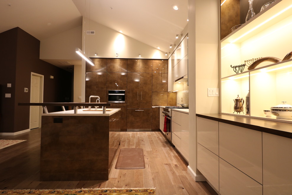 Photo of a large contemporary l-shaped eat-in kitchen in New York with an undermount sink, flat-panel cabinets, white cabinets, panelled appliances, medium hardwood floors, with island and brown floor.