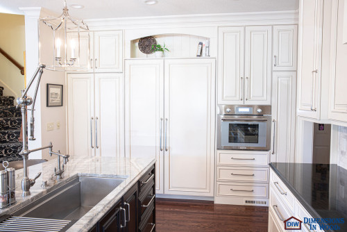Bright traditional kitchen with white RTA cabinets, panel-ready refrigerator doors, built-in wall oven, and a marble farmhouse sink.