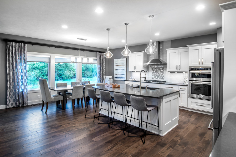 Inspiration for a transitional l-shaped eat-in kitchen in Other with an undermount sink, white cabinets, onyx benchtops, subway tile splashback, stainless steel appliances, dark hardwood floors and with island.