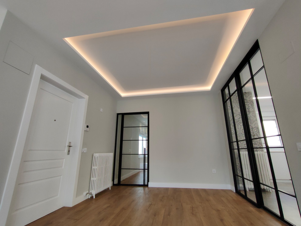 Imagen de hall tradicional renovado grande con paredes grises, suelo de madera en tonos medios, puerta simple, puerta blanca y suelo marrón