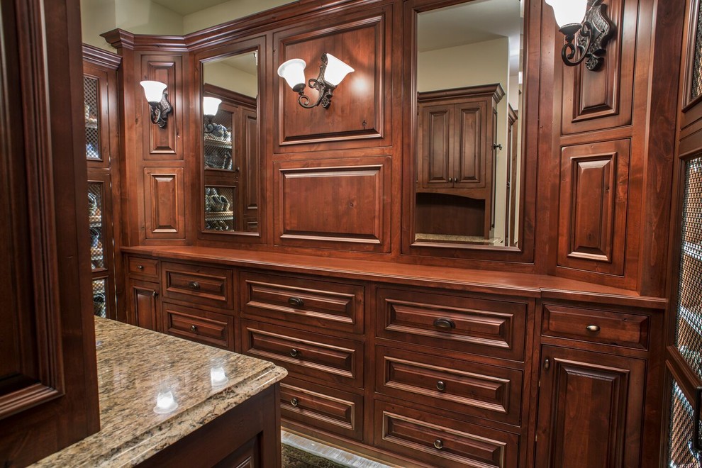 Design ideas for a large traditional gender-neutral walk-in wardrobe in Charlotte with raised-panel cabinets and dark wood cabinets.