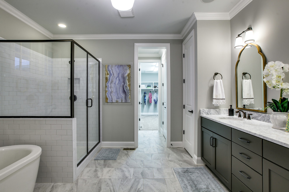 Photo of a country master bathroom in Nashville with shaker cabinets, a freestanding tub, a corner shower, white tile, subway tile, grey walls, marble floors, an undermount sink, marble benchtops, grey floor and a hinged shower door.