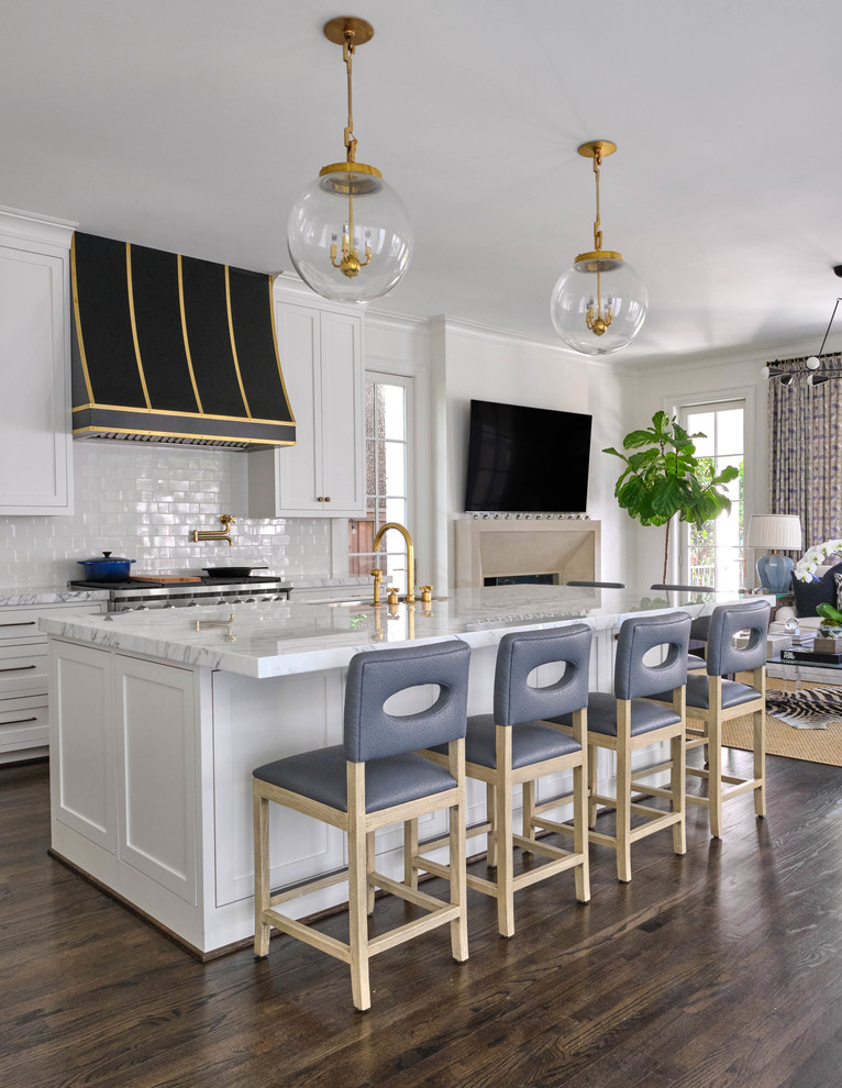 This is an example of a transitional galley eat-in kitchen in Dallas with recessed-panel cabinets, white cabinets, white splashback, subway tile splashback, stainless steel appliances, dark hardwood floors, with island, brown floor and white benchtop.
