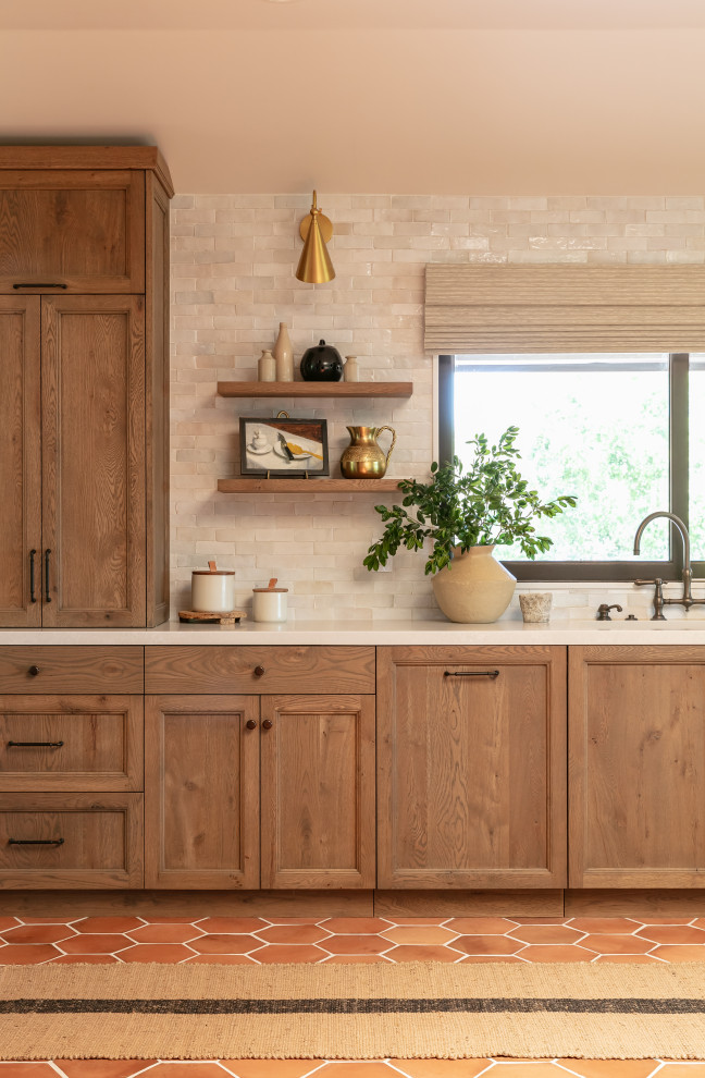 Example of a huge tuscan u-shaped terra-cotta tile and orange floor open concept kitchen design in Santa Barbara with an integrated sink, recessed-panel cabinets, medium tone wood cabinets, quartz countertops, white backsplash, terra-cotta backsplash, paneled appliances, an island and beige countertops