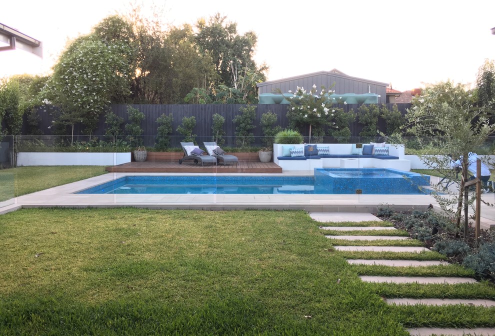 Large modern backyard rectangular pool in Melbourne with concrete pavers and a hot tub.