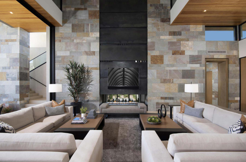 This is an example of an expansive contemporary open concept family room in Phoenix with white walls, a two-sided fireplace and a wall-mounted tv.