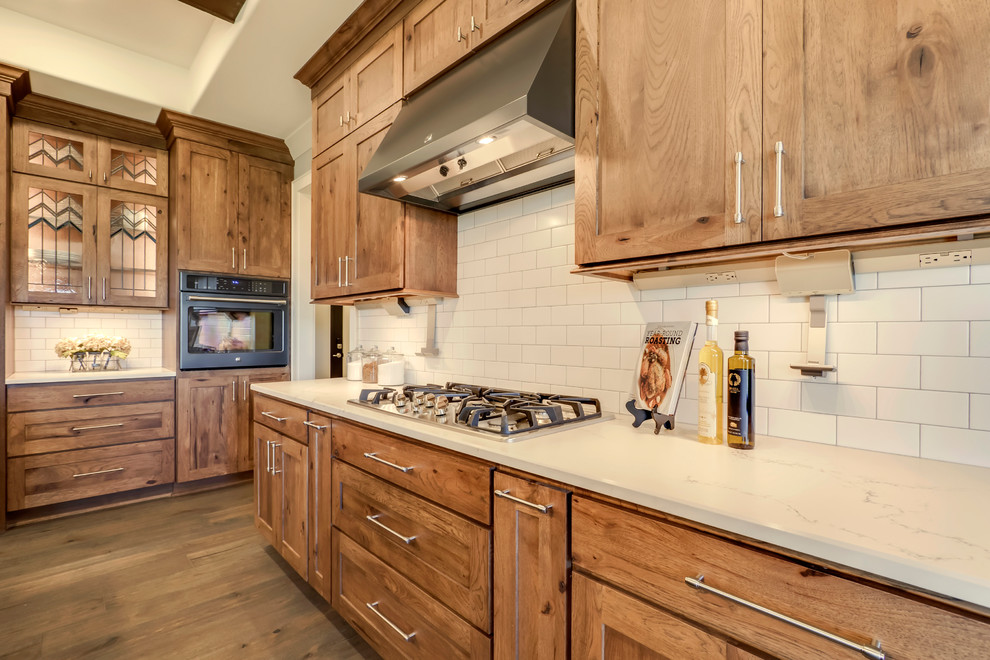 Mid-sized arts and crafts l-shaped open plan kitchen in Other with an undermount sink, shaker cabinets, medium wood cabinets, quartz benchtops, white splashback, subway tile splashback, stainless steel appliances, with island and white benchtop.