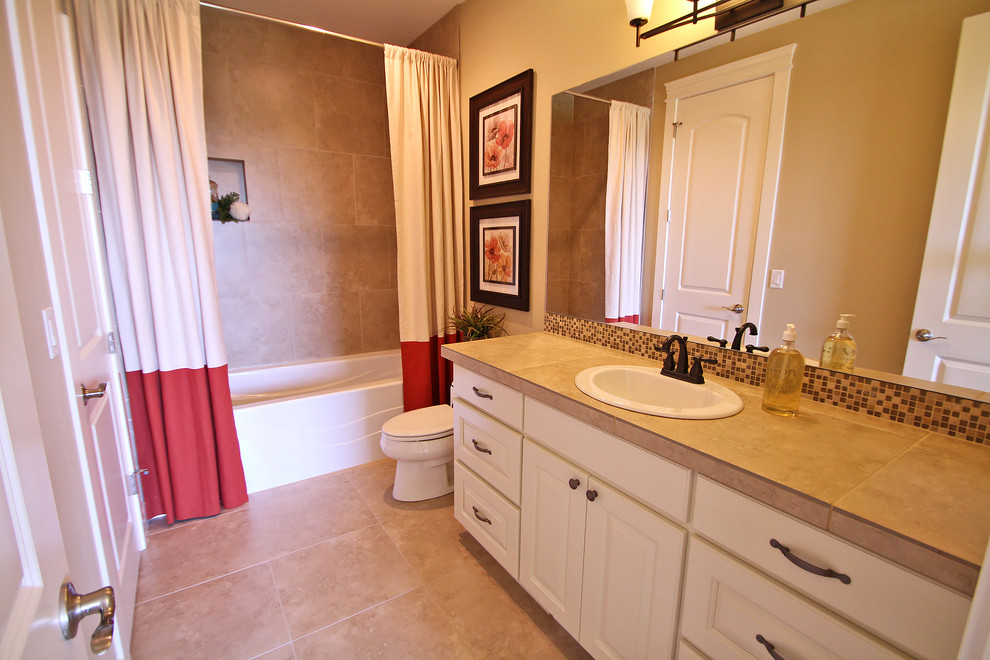 Mid-sized traditional master bathroom in Portland with furniture-like cabinets, white cabinets, a drop-in tub, an alcove shower, a one-piece toilet, beige tile, stone tile, beige walls, travertine floors, a drop-in sink and tile benchtops.