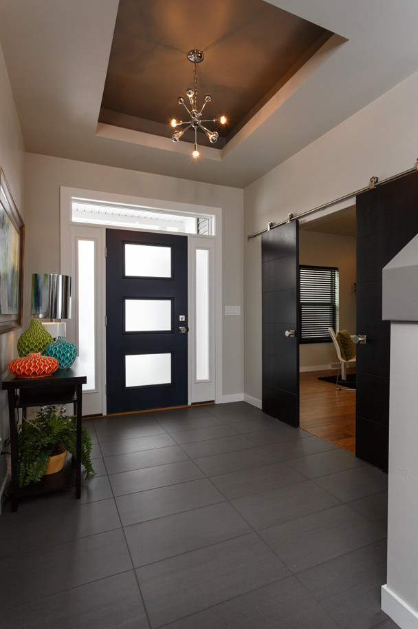 Large minimalist porcelain tile and gray floor foyer photo with beige walls and a black front door