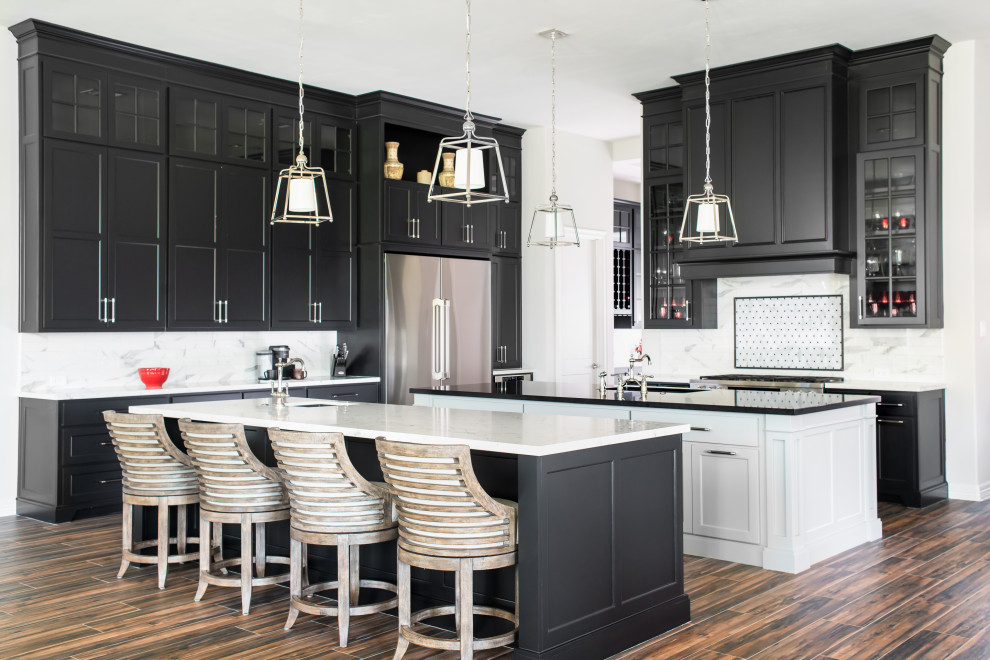 Inspiration for a large transitional l-shaped kitchen in Houston with shaker cabinets, black cabinets, white splashback, stainless steel appliances, porcelain floors, multiple islands, brown floor, quartz benchtops, an undermount sink, multi-coloured benchtop and marble splashback.