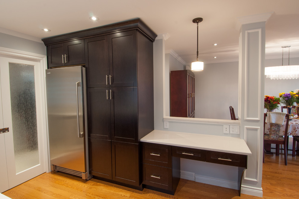 Large transitional galley light wood floor enclosed kitchen photo in Toronto with a single-bowl sink, shaker cabinets, dark wood cabinets, quartzite countertops, beige backsplash, stone tile backsplash, stainless steel appliances and an island